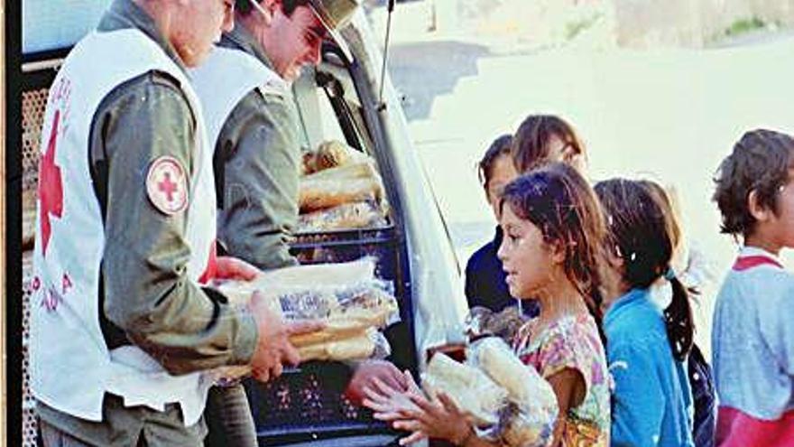 Voluntarios de Cruz Roja reparten alimentos entre los niños durante la riada de 1987.