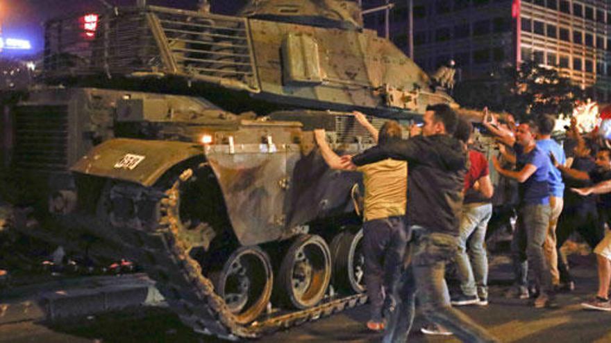 Varios turcos intentan frenar un tanque militar.