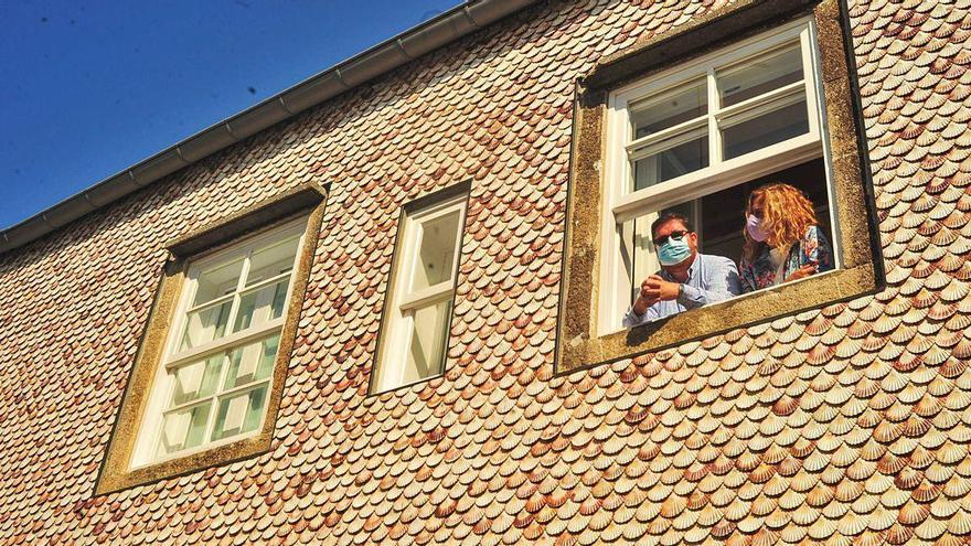 Carlos Iglesias y Carmela Silva se asoman por una ventana a la fachada de conchas de vieira de una de las viviendas.