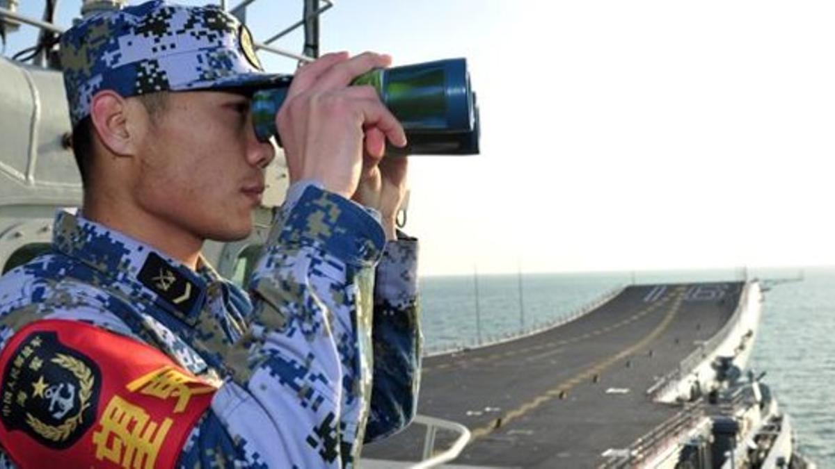 Un soldado chino vigila con sus prismáticos en el portaaviones 'Liaoning', tras atracar en Sanya, en una foto facilitada este viernes.