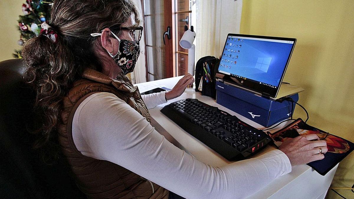 Una empleada teletrabaja frente a su ordenador en su domicilio.