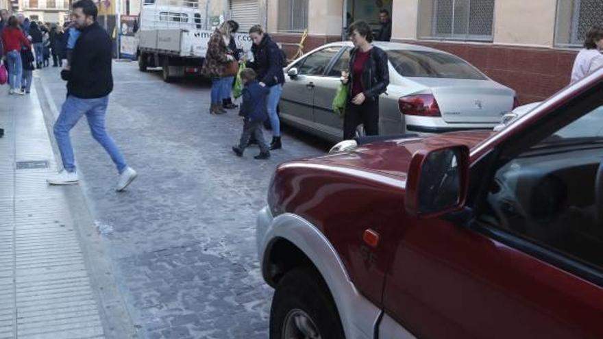 Un vehículo espera ante la llegada al colegio de los padres y madres con sus hijos.