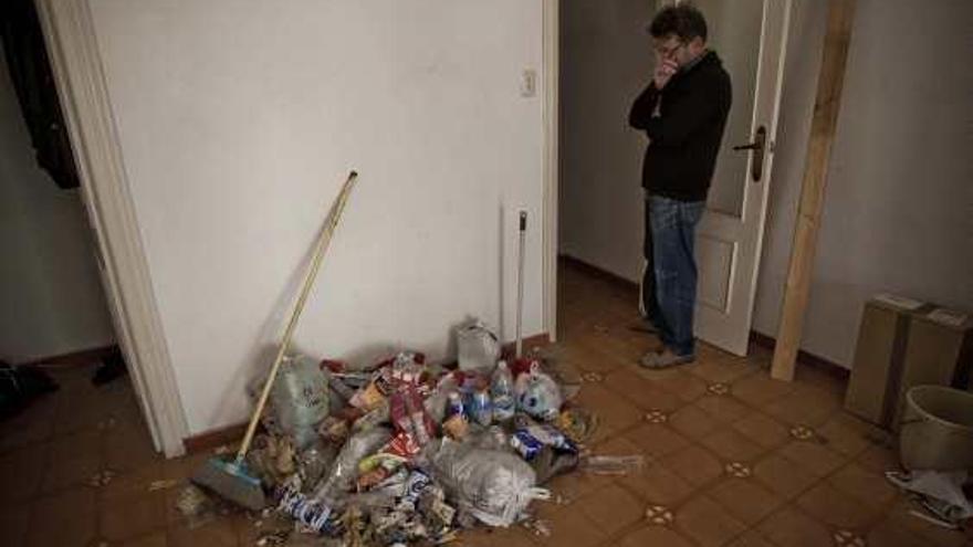 Imágenes de la habitación en cuya puerta apareció ahorcado el desahuciado y del dueño de la casa pensativo ante una montaña de basura en el salón de la vivienda.