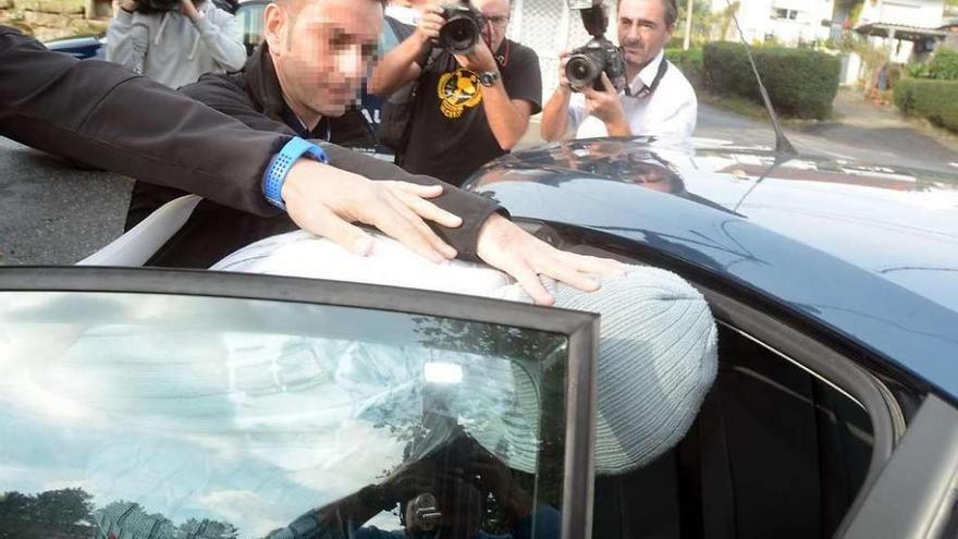 Unos agentes introducen en un coche a José Lusquiños tras ser detenido en su casa. // Rafa Vázquez