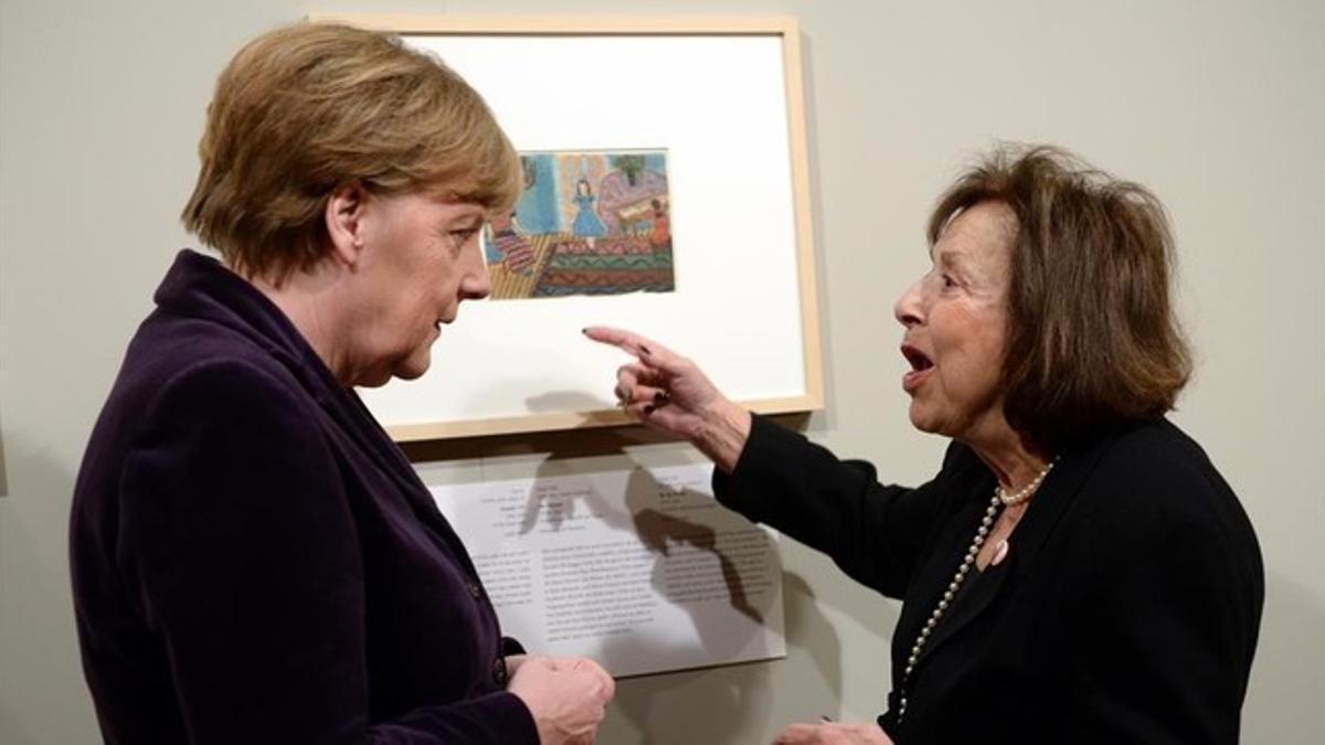 La artista Nelly Toll, conversa con la canciller alemana, Angela Merkel, en la inauguración de la exposición Arte del Holocausto en Berlín.