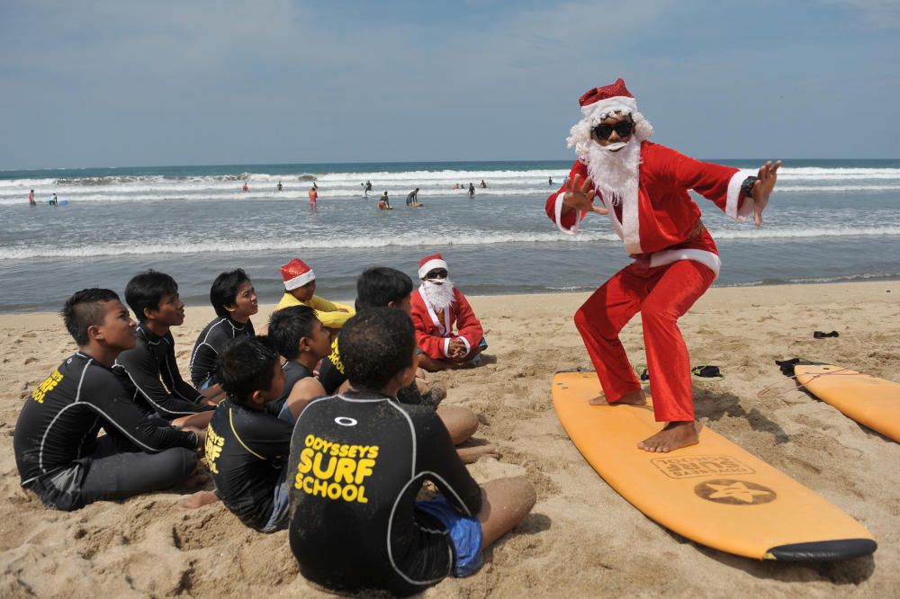 Un instructor de surf da clases a huérfanos vestido de Papa Noel en Kuta Beach, Bali, Indonesia.