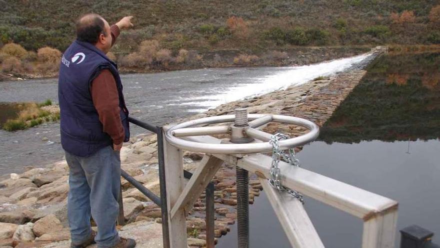 Una persona muestra el paso de agua en la presa de Tinico.