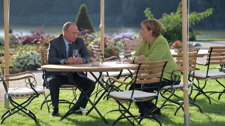 Vladimir Putin y Angela Merkel dialogan ayer durante su encuentro en Berlín. // Efe