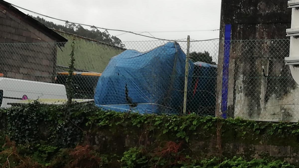 El autobús, cubierto por una lona, es custodiado en Lourizán