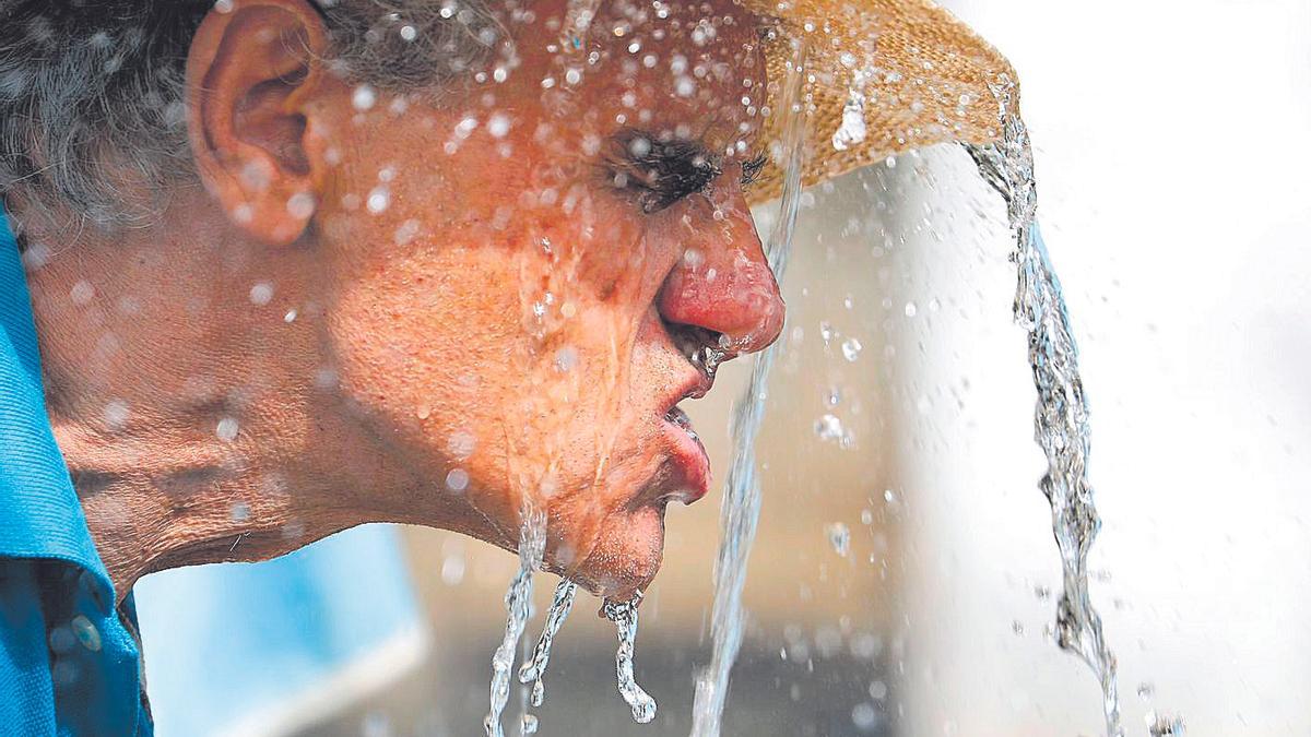 Un hombre se refresca ante las altas temperaturas.