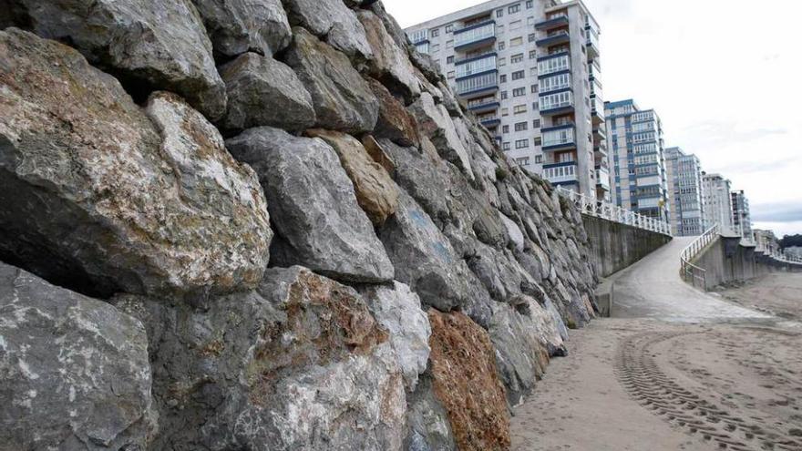 La escollera de la playa de Salinas, con varios edificios al fondo.