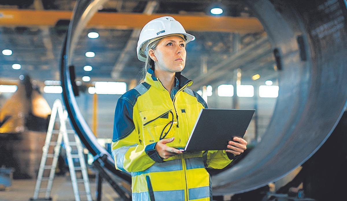 Female Industrial Engineer in the Hard Hat Uses Laptop Computer