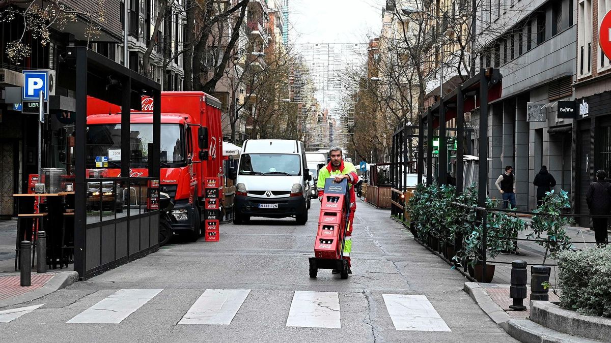 Un repartidor de bebida pasa junto a las terraza instaladas en la calle Ponzano de Madrid.