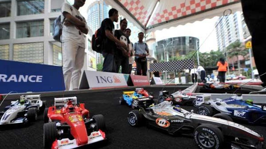 Aficionados a la Fórmula 1 observan réplicas en miniatura de los monoplazas en el circuito de Sepang, en Malasia.