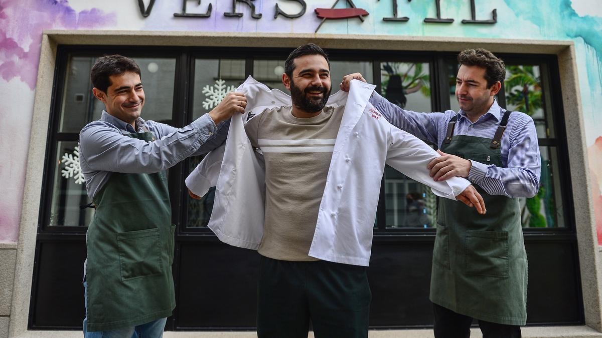 José Luis (izquierda) y David (derecha) ayudan a su hermano Alejandro a ponerse la chaquetilla de la estrella Michelín.