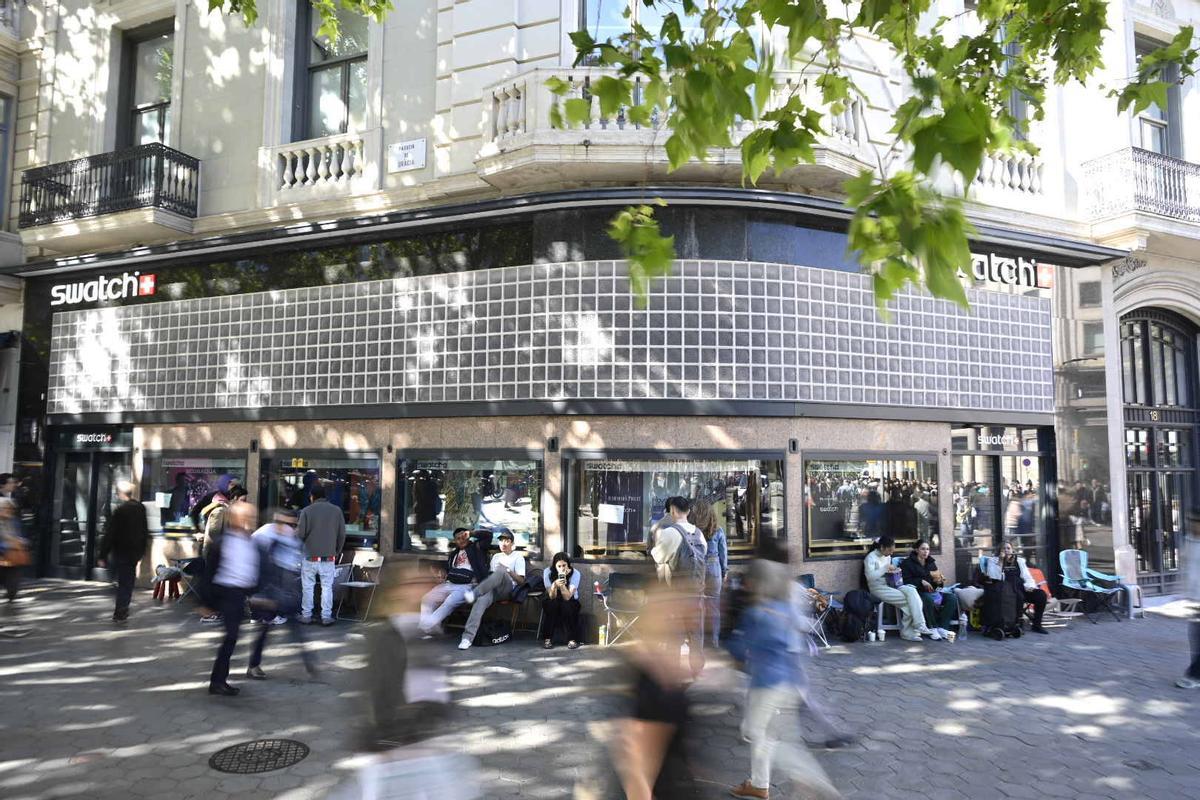 Cola de posibles compradores en el exterior de la tienda Swatch en Paseo de Gracia esquina Gran Vía, cerrada por motivos de seguridad según anuncia un cartel, a raíz de la venta del modelo Swatch creado en colaboración con la firma de relojes de lujo Audemars Piguet