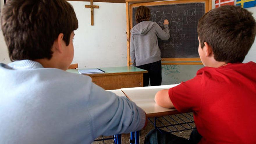 Alumnos en un aula presidida por un crucifijo. // T.G.