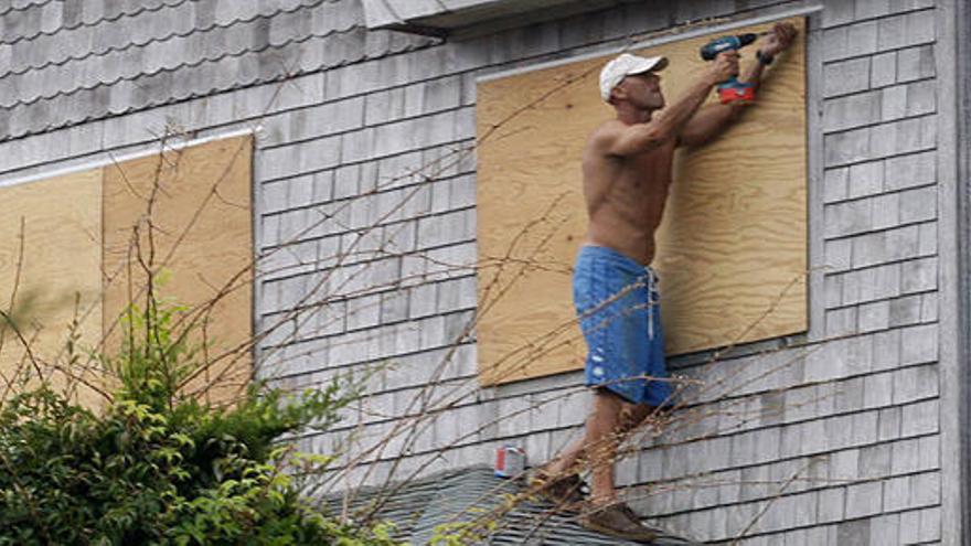 Un hombre sella las ventanas de una vivienda en Buxton, Carolina del Norte (EEUU)