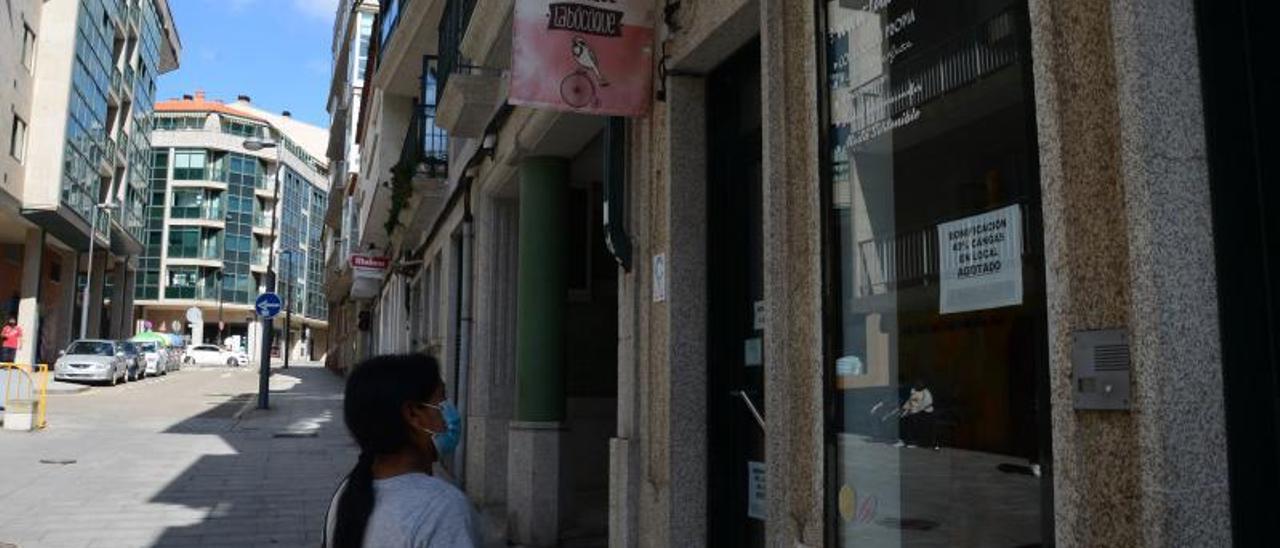 Una mujer, frente a un escaparate de Cangas con un cartel alusivo al bono comercio. |   // G.NÚÑEZ