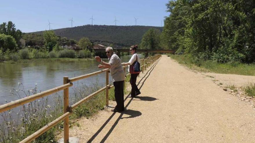 Un hombre y una mujer observan el río, todavía con abundante caudal, desde el paseo.