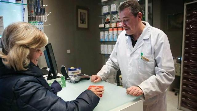 El farmacéutico ovetense José Manuel González del Valle dispensa un antigripal a Mercedes Álvarez.