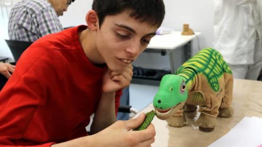 Un jove amb trastorn mental interactuant amb un peluix de dinosaure, un robot per estimular els usuaris