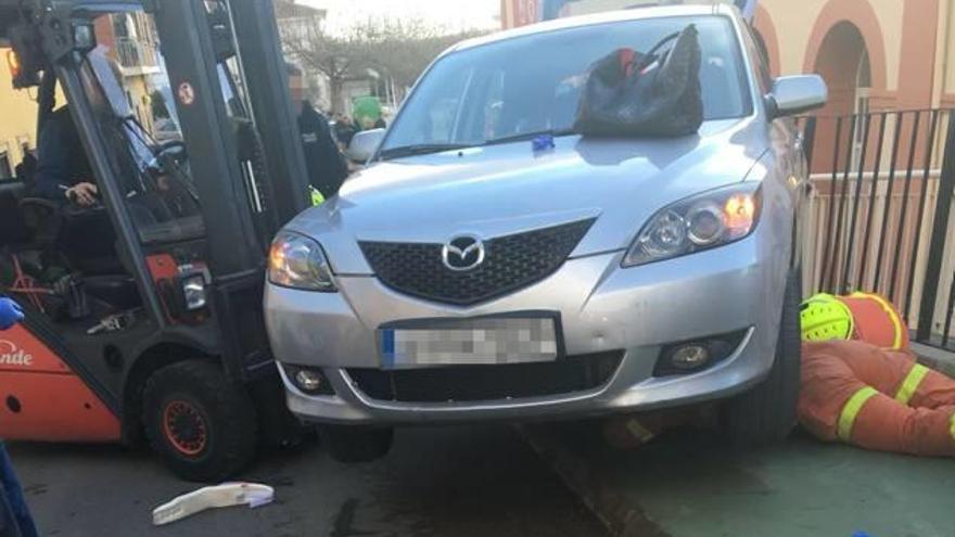 Los bomberos tratan de sacar a la mujer bajo el coche.