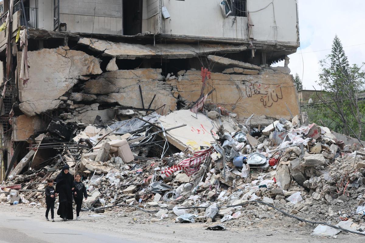 Personas caminan junto a los escombros de un edificio dañado por un ataque aéreo israelí en la aldea de Jibchit, al sur del Líbano.