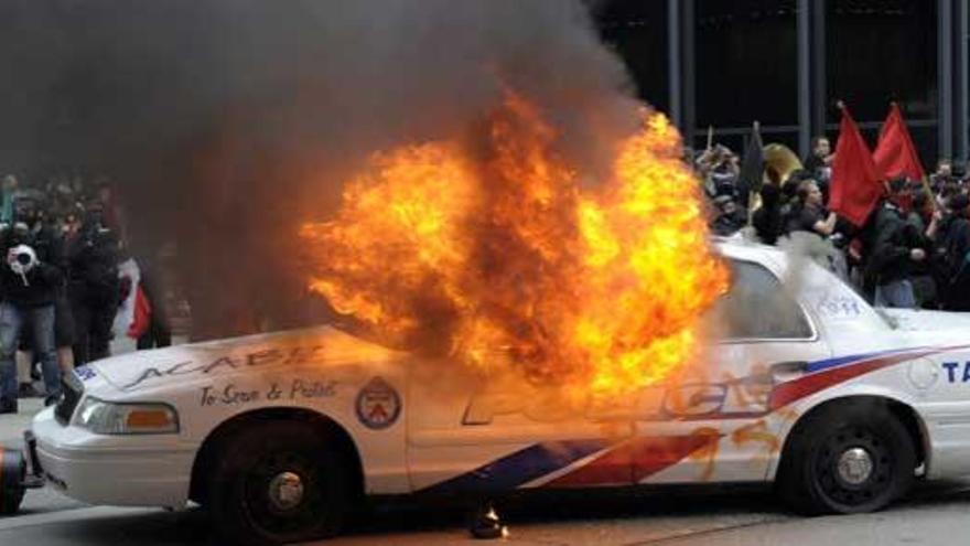Un coche de la policía, en llamas tras los disturbios.