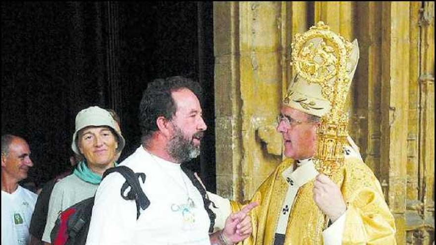 El arzobispo Carlos Osoro saluda a un peregrino ante la catedral de Oviedo.