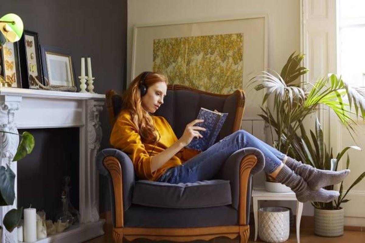 Cuarentena: mujer en casa leyendo y escuchando música