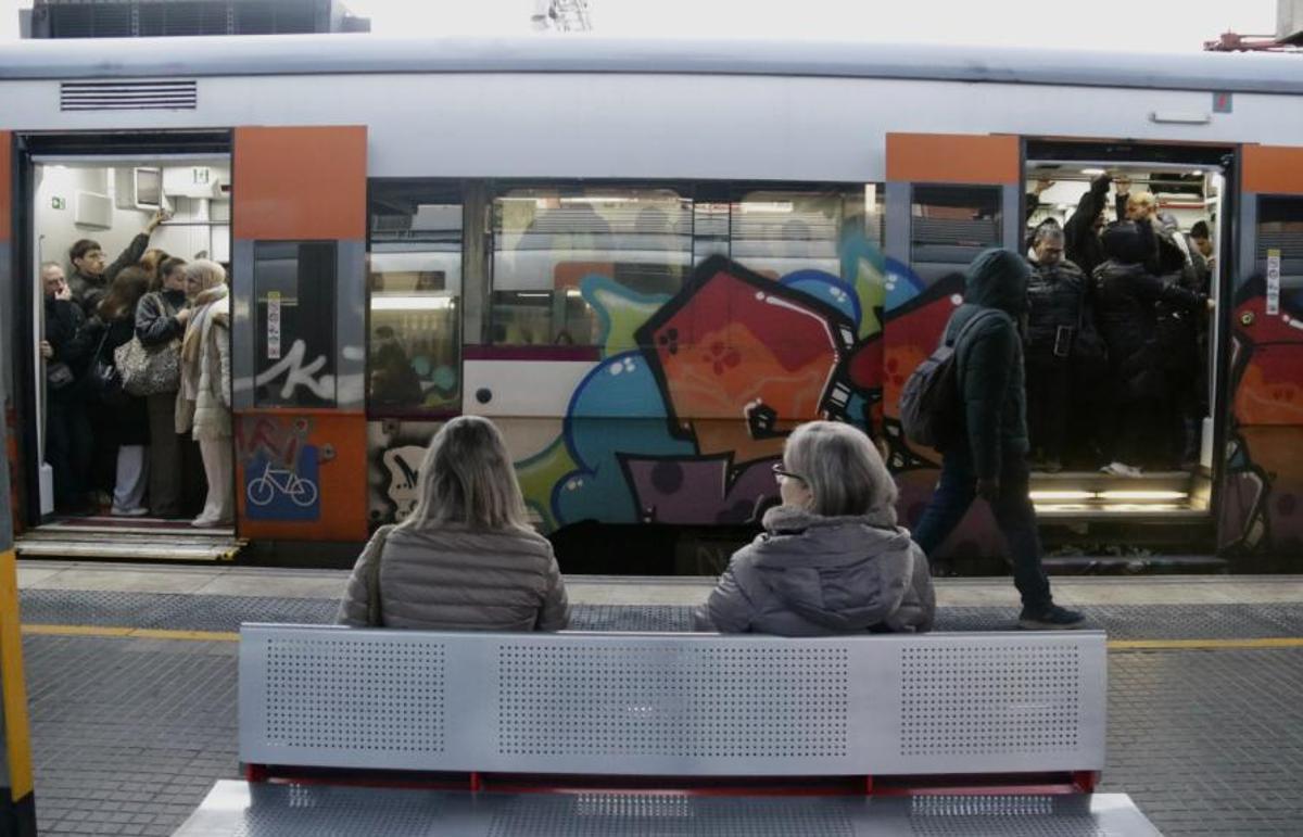 Dues usuàries de Rodalies assegudes a un banc a l'estació de Mataró, resignades de no agafar el comboi, que és a a punt de tancar portes ple de gent