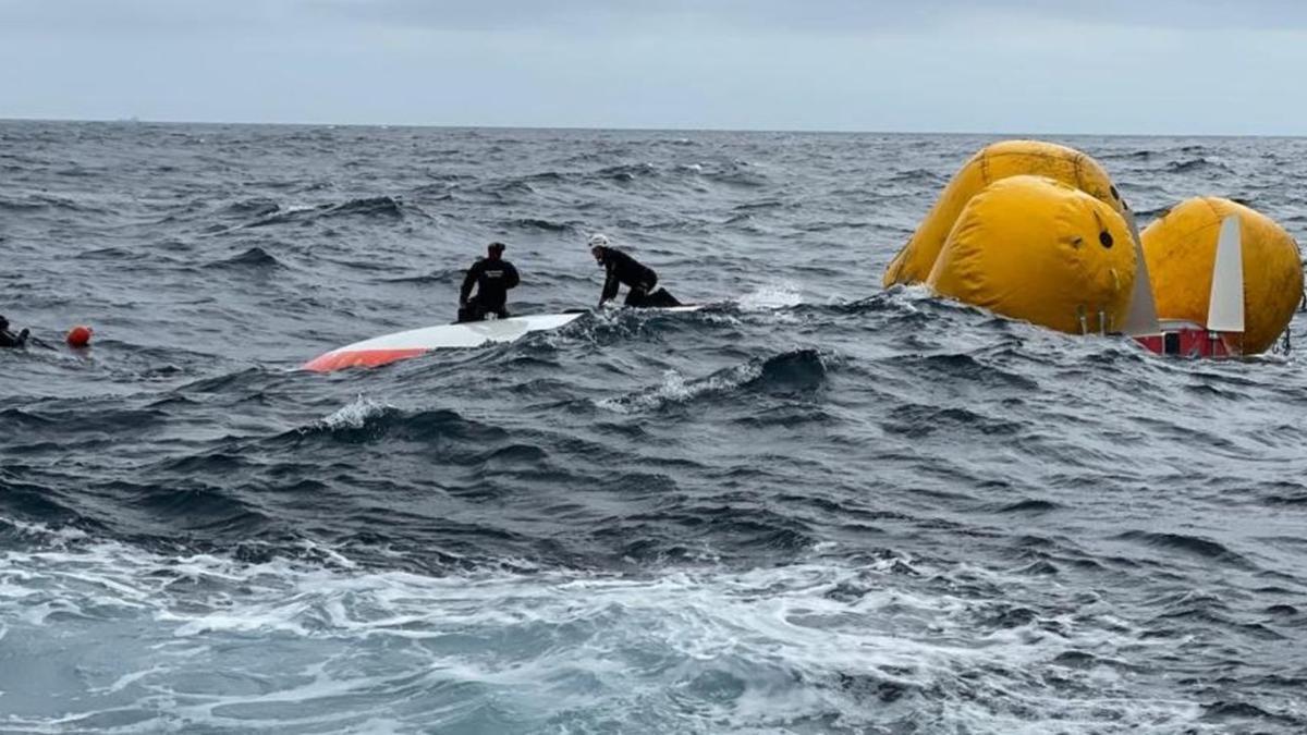 Dos buzos, sobre el casco del velero, mientras se colocaban los globos para evitar su hundimiento. |   // SALVAMENTO MARÍTIMO