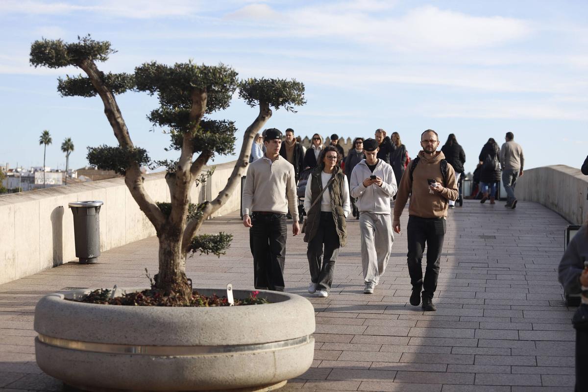 Varias personas caminan al sol en el Puente Romano de Córdoba.