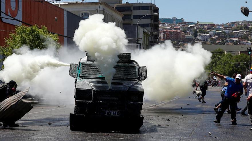 Un camión de la policía libera gas ante los manifestantes.