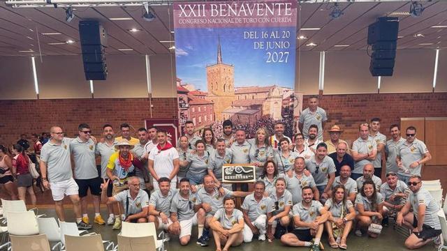 Miembros de la Asociación Benaventana del Toro Enmaromado posan frente al cartel anunciador del Congreso de 2027. | CEDIDA