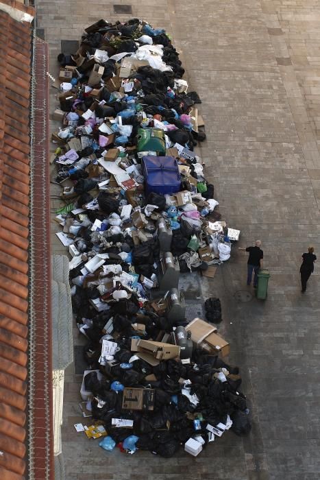 A waiter pushes a rubbish bin past a pile of ...