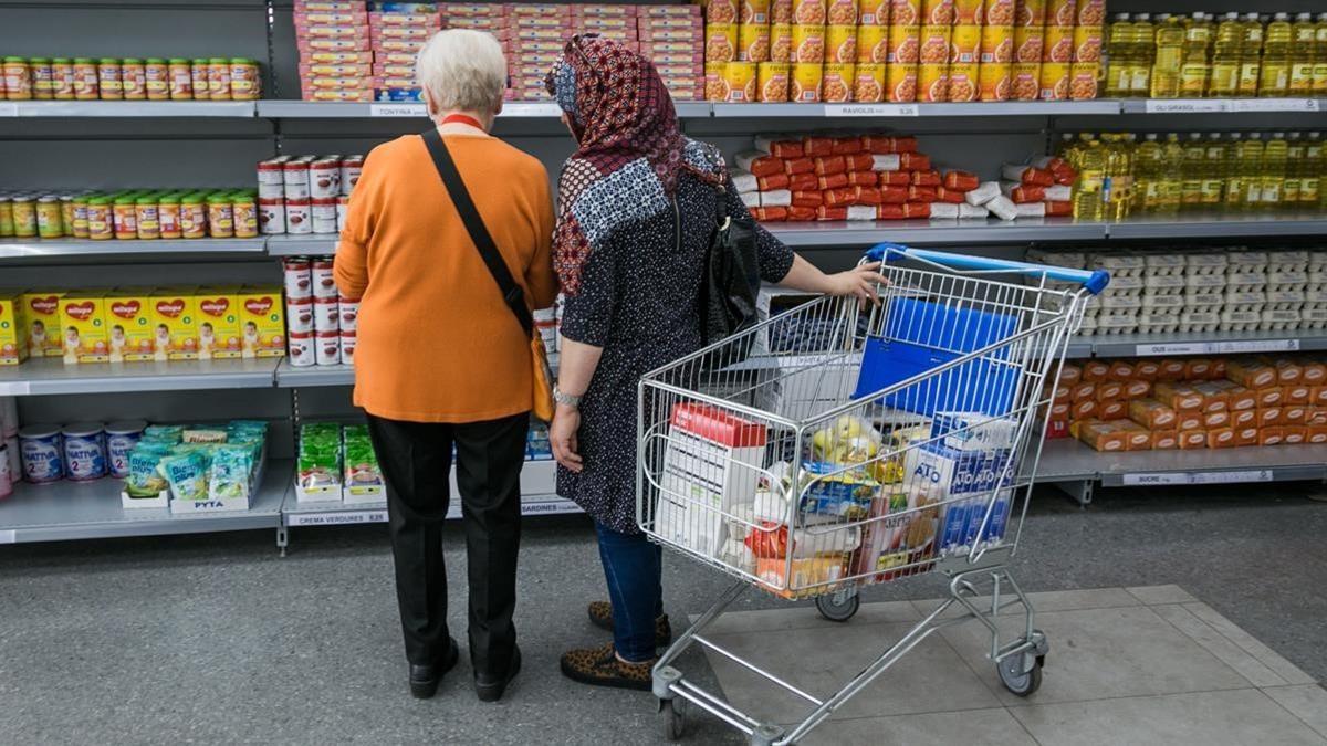 Dos personas observan las estanterías de un economato para familias sin recursos.