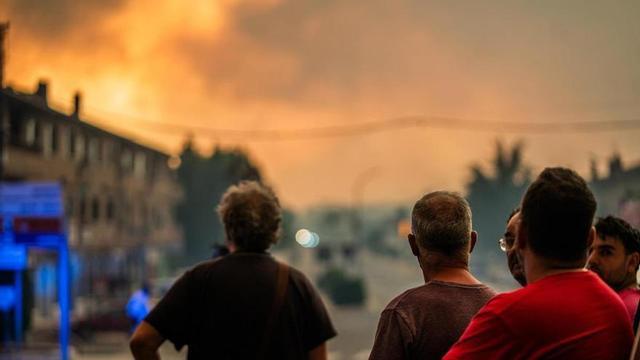 Diverses persones observen el foc durant les tasques d’extinció de l’incendi forestal, a 25 de juliol del 2026, a La Adrada, Àvila, Castella i Lleó (Espanya).