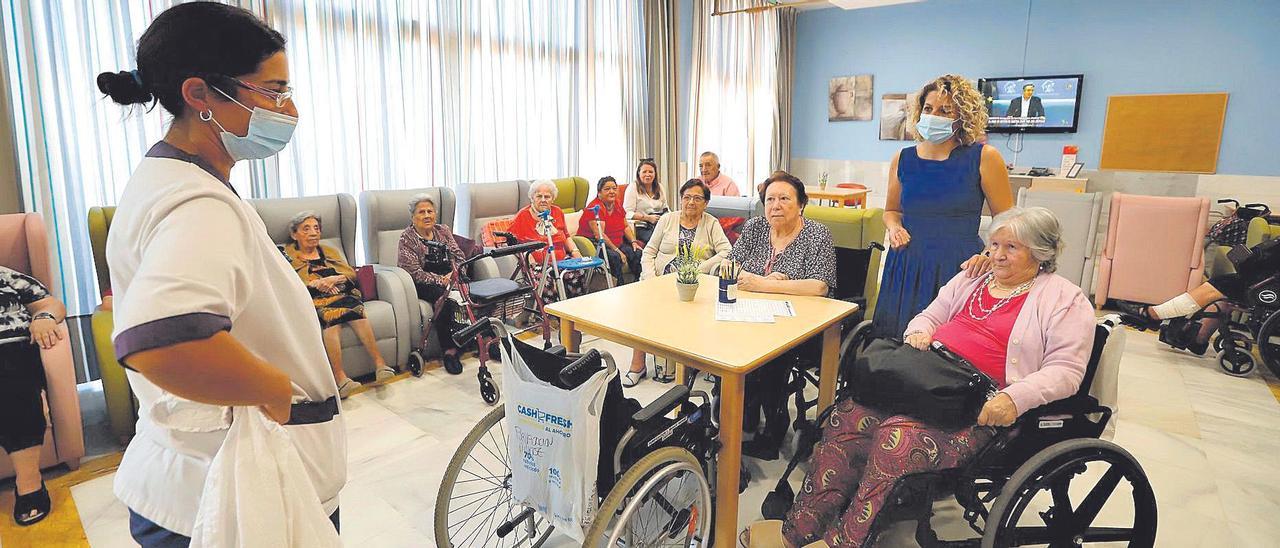 La directora de la residencia Vitalia Guadalquivir y una de las trabajadoras conversan con un grupo de usuarias en el salón.