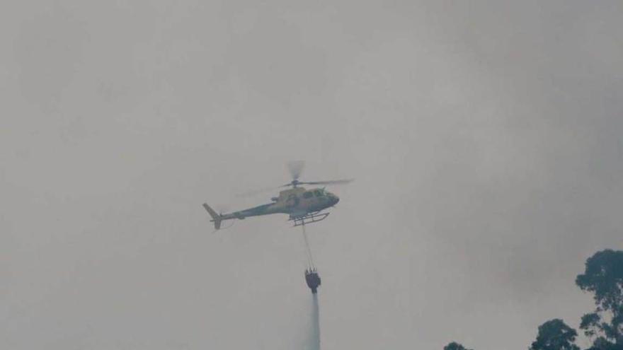 Arriba, un helicóptero vacía una bolsa de agua sobre el incendio del Escañorio; sobre estas líneas, un vehículo de los bomberos en Salinas.