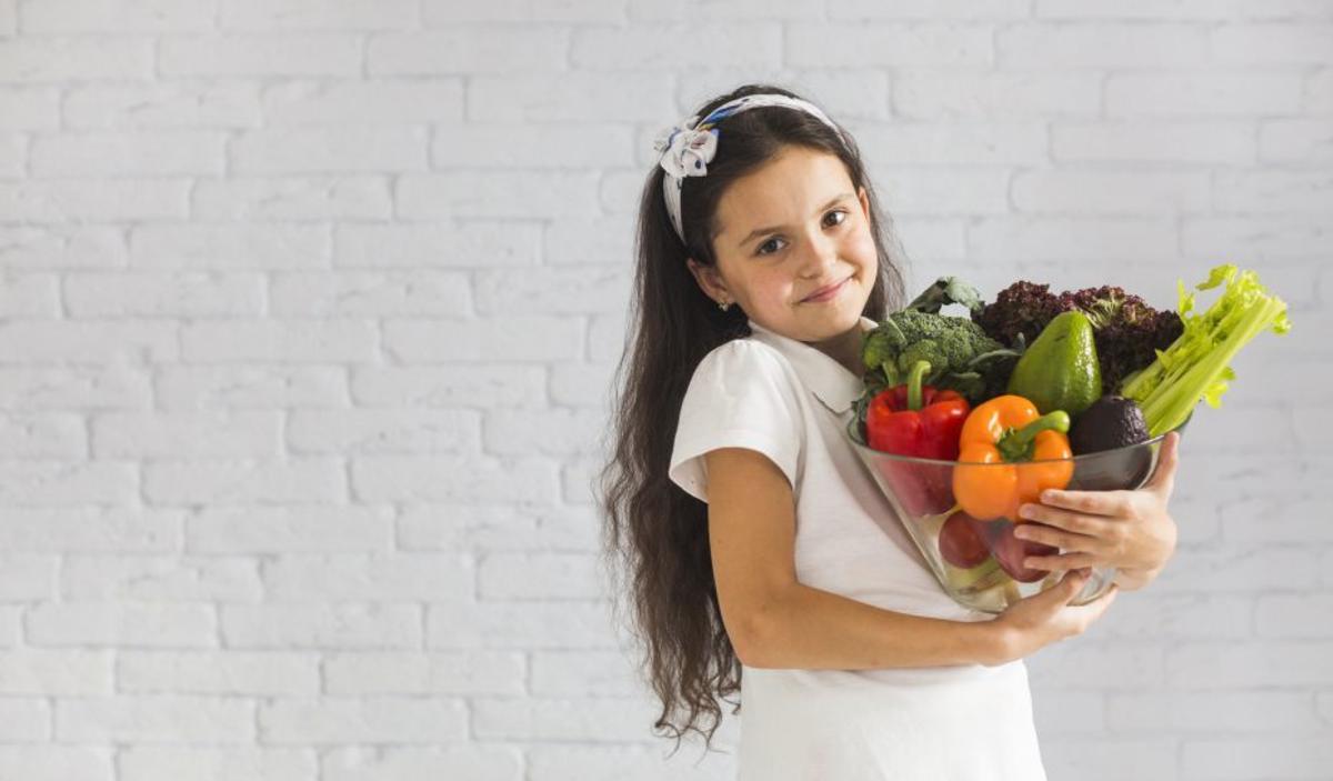 Una niña con un bol de verduras. | | FREEPIK