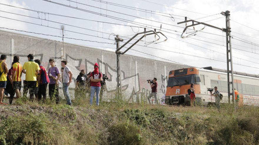 Un grup de persones aturant un tren de rodalies a l&#039;entrada de Girona.