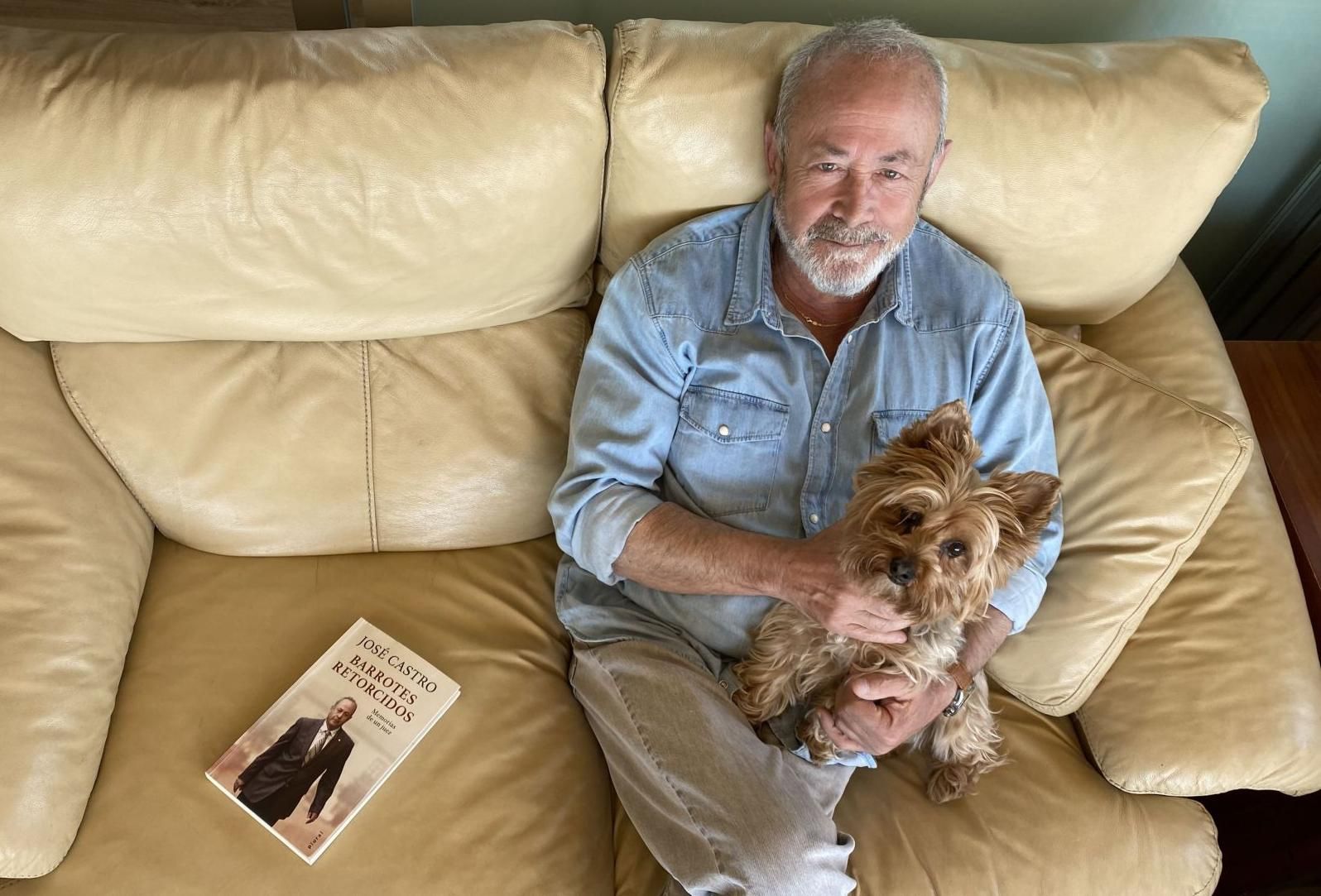 José Castro posa con su mascota , al lado un ejemplar de su autobiografía, en el salón de su casa, en Palma.