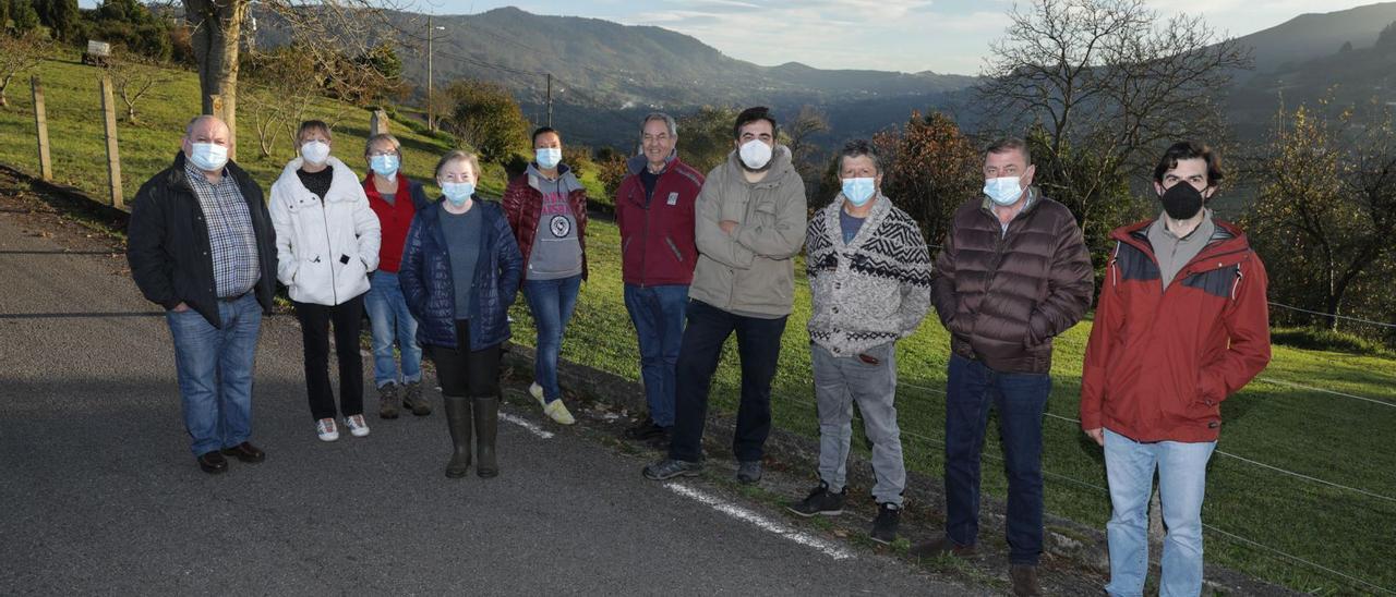 Por la izquierda, Desiderio Blanco, María Jesús Suárez, Pepa Geijo, Teresa Geijo, Patricia Winter, Manuel Rodríguez, Lorenzo Linares y Manuel Ángel Fano, vecinos de Baldornón, con Miguel Llanos, de La Pedrera, y Javier Iglesias, de Vega, posando juntos ayer en Caldones con el gran valle que une sus parroquias de fondo. | Juan Plaza