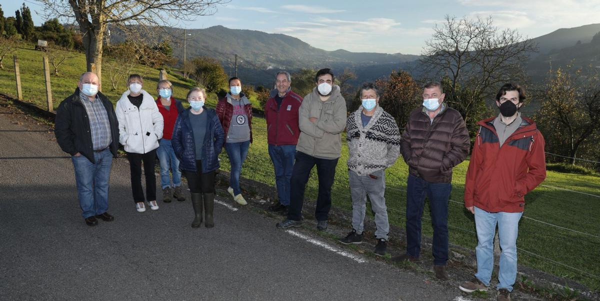 Por la izquierda, Desiderio Blanco, María Jesús Suárez, Pepa Geijo, Teresa Geijo, Patricia Winter, Manuel Rodríguez, Lorenzo Linares y Manuel Ángel Fano, vecinos de Baldornón, con Miguel Llanos, de La Pedrera, y Javier Iglesias, de Vega, posando juntos ayer en Caldones con el gran valle que une sus parroquias de fondo. | Juan Plaza