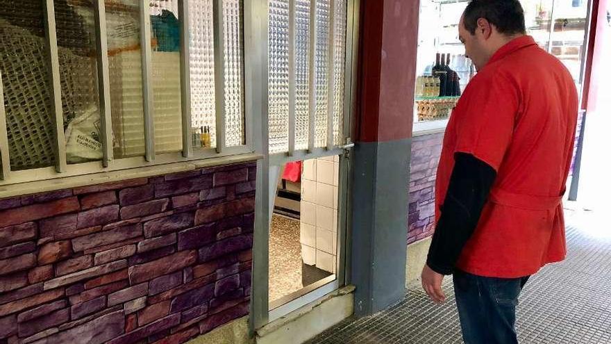 El propietario observa la puerta forzada para entrar en su negocio. // Bernabé