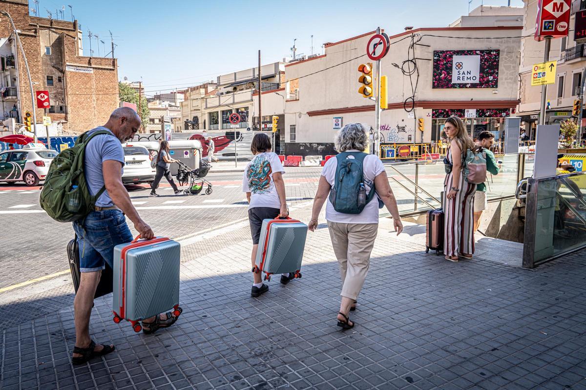 Turistas con maletas junto a la parada de metro de Collblanc.