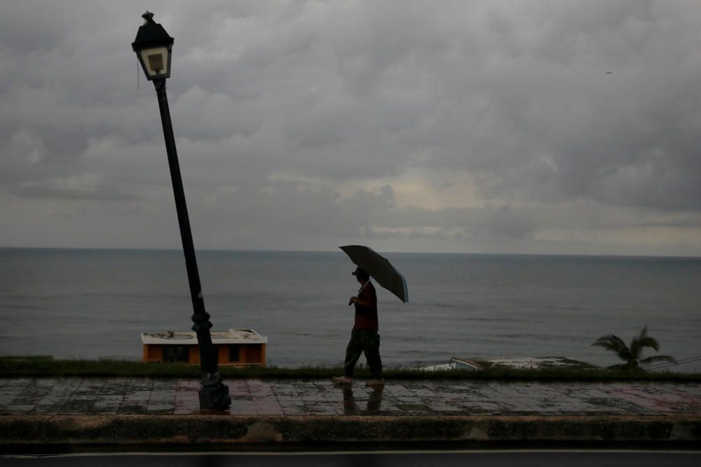 A man walks with an umbrella in the Hurricane ...