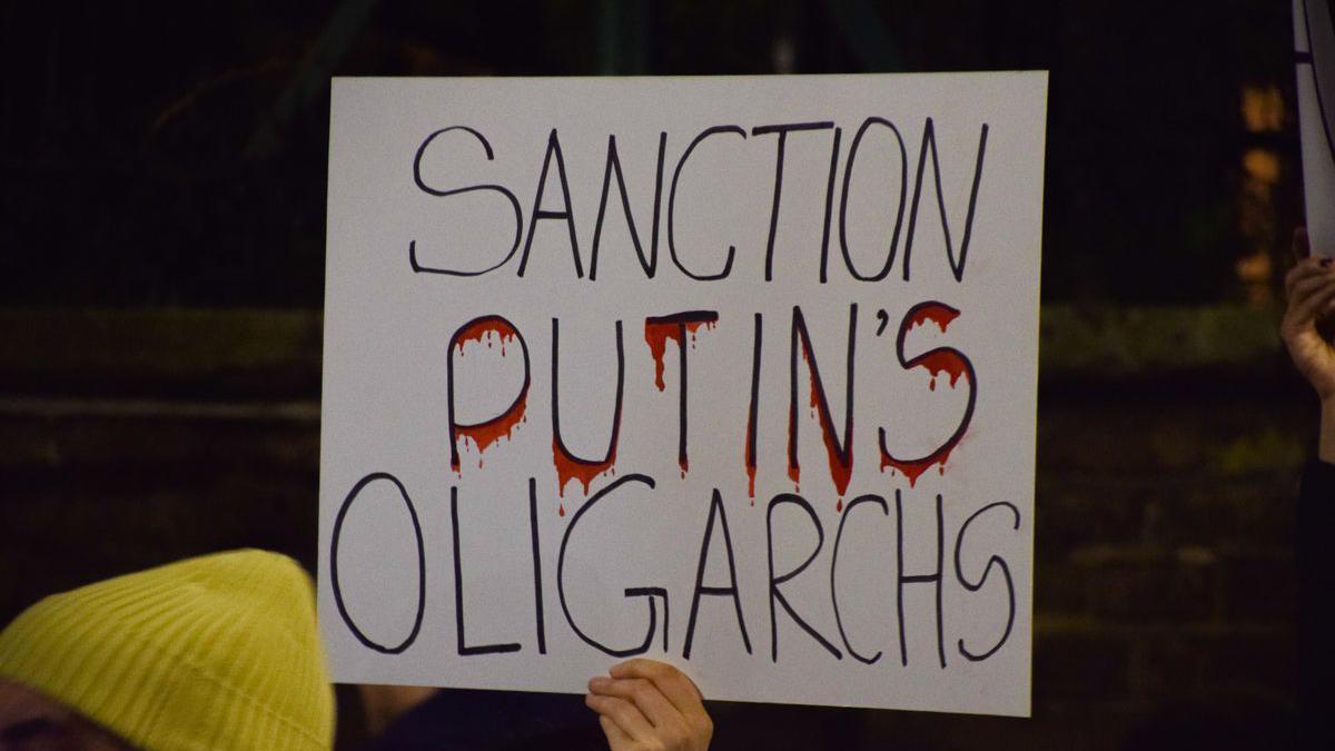 Un manifestante sostiene una pancarta, sancionar a los oligarcas de Putin, frente a la embajada rusa en Londres.